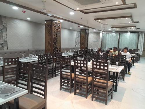HOTEL TASTE OF INDIA في آغْرا: غرفة طعام مع أشخاص يجلسون على الطاولات