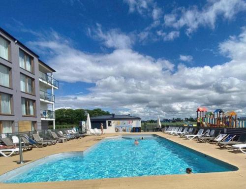 een groot zwembad met stoelen en een hotel bij APARTAMENT BLUE II, Marynarska 10, Sarbinowo in Sarbinowo