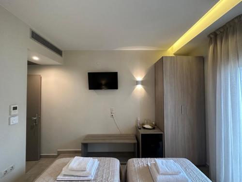 a bedroom with two beds and a tv on the wall at Yulia Luxury Apartments in Ouranoupoli