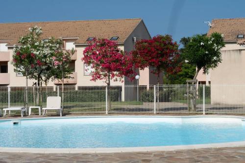 une piscine avec des fleurs roses en face d'une clôture dans l'établissement Villa ALOHA-65m2 garden/Swimmingpool - 500m Beach, à Moriani-Plage
