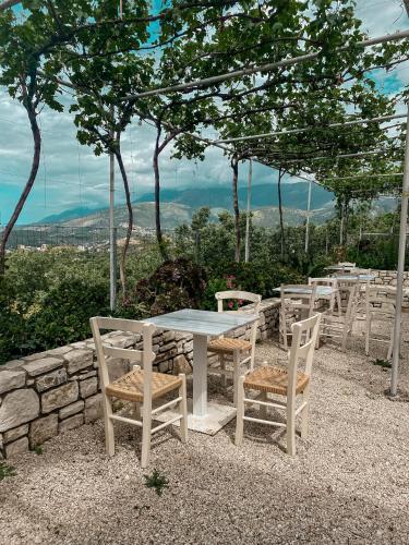 a white table and chairs and a stone wall at ELÉA Guesthouse himare in Himare