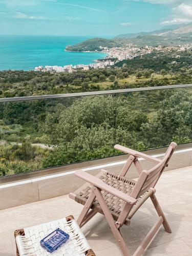 a rocking chair on a balcony with a view of the ocean at ELÉA Guesthouse himare in Himare