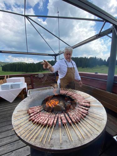 a woman standing in front of a grill at Malga Millegrobbe Nordic Resort in Lavarone