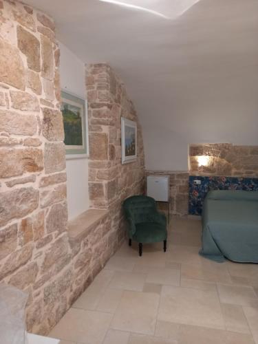 a room with a stone wall and a green chair at Suite Duomo Trani 8 in Trani