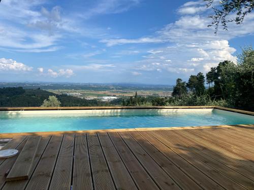 a swimming pool with a wooden deck and a view at Rivolta home in Buti