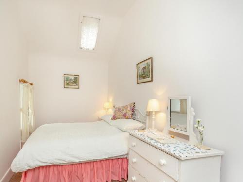 ein Schlafzimmer mit einem Bett und eine Kommode mit einem Spiegel in der Unterkunft The Cottage in Slickly