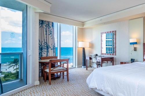 a hotel room with a bed and a desk and a window at TRUMP INTL 2 BEDROOM APARTMENT 1600 Sqf Ocean and Bay View in Miami Beach