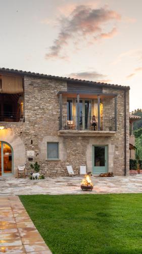 a stone house with a fire pit in a yard at ECOTurisme Can Buch HOTEL in Sant Aniol de Finestras