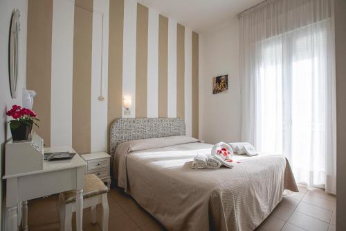 a bedroom with a bed and a desk and a window at Hotel Ronchi in Cervia