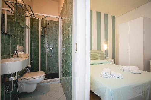 bagno con letto, doccia e servizi igienici di Hotel Ronchi a Cervia