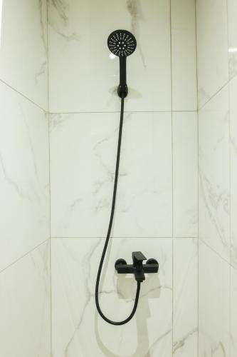 a shower with a shower head on a white tile wall at Uphill Unique Boutique Suites in Skiathos Town