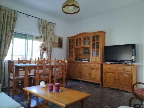 sala de estar con mesa de comedor y TV en Villa Antonia en Chipiona