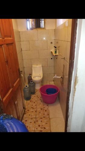 a small bathroom with a toilet and a red bucket at Amar ak house in Mombasa