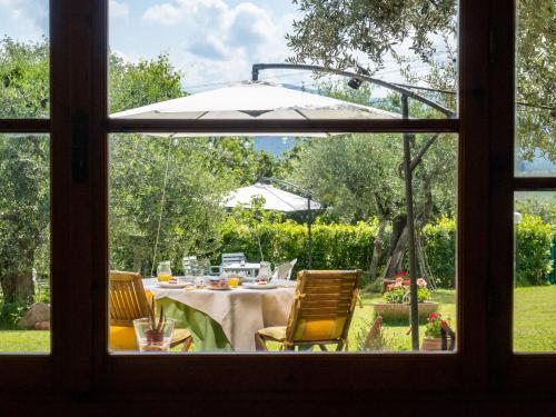 a table with chairs and an umbrella viewed through a window at B&B Casa Decimo in Greve in Chianti