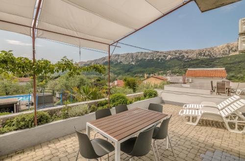 a patio with a wooden table and chairs on a roof at Apartmani M in Baška