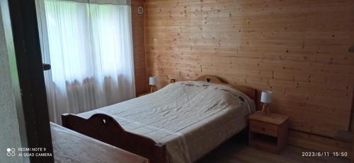 1 dormitorio con 1 cama con pared de madera en Le Randonneur en Flumet