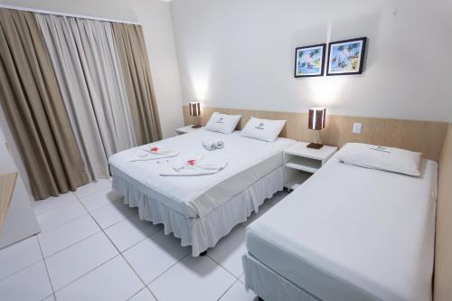a hotel room with two beds and two tables at Hotel Jangadas in Águas Belas