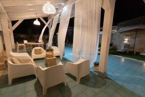 - un pavillon avec des chaises blanches et une table dans l'établissement SICILY SUN CON ACCESSO SPIAGGIA, à Santa Maria Del Focallo