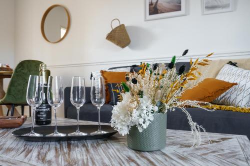 a table with wine glasses and a vase with flowers at La Petite Plume - PrestiPlace Tours in Tours