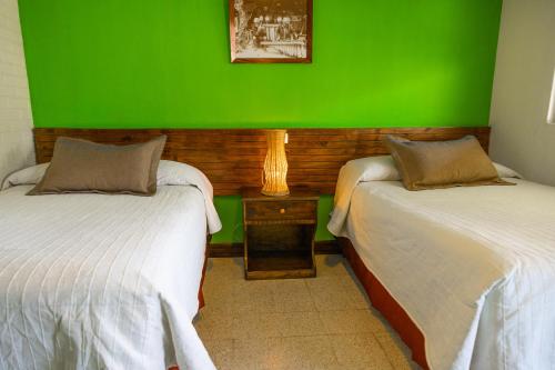 two beds in a room with a green wall at Hotel y Centro de Convenciones Jardines del Lago in Panajachel