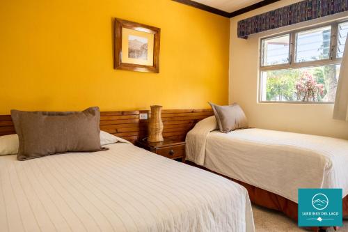 two beds in a room with yellow walls at Hotel y Centro de Convenciones Jardines del Lago in Panajachel