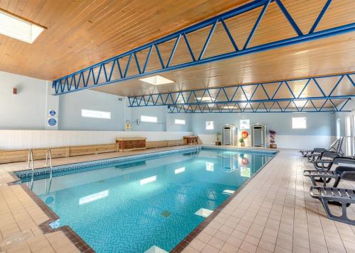 a large swimming pool with chairs in a building at Brixham Holiday Park in Brixham