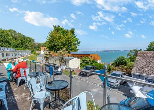 a balcony with tables and chairs and a view of the water at Brixham Holiday Park in Brixham