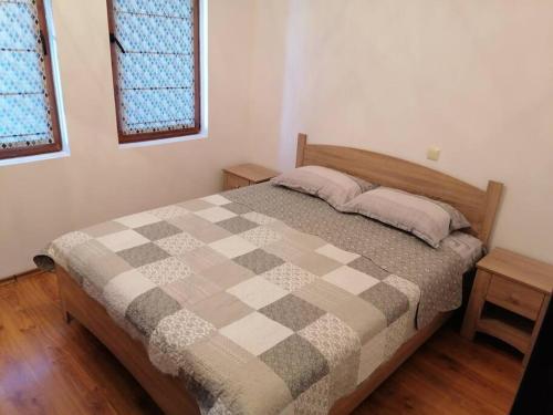 a bedroom with a bed with a checkered blanket at Олимп - апартамент с две спални in Sveti Vlas