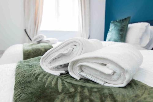 a pile of towels sitting on top of a bed at CLOUDSTAYS - Luxury 3 Bed Townhouse - Sleeps upto 8 Birmingham City and Central - Free Parking & WIFI in Birmingham