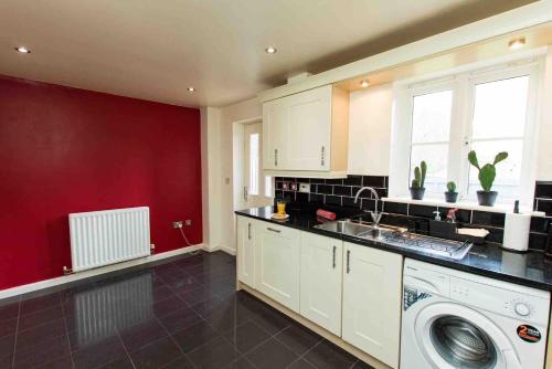 a kitchen with a washing machine and a red wall at Cloudstays Birmingham Luxury Townhouse 2 lakes sleeps upto 8 Free Parking & WIFI in Birmingham