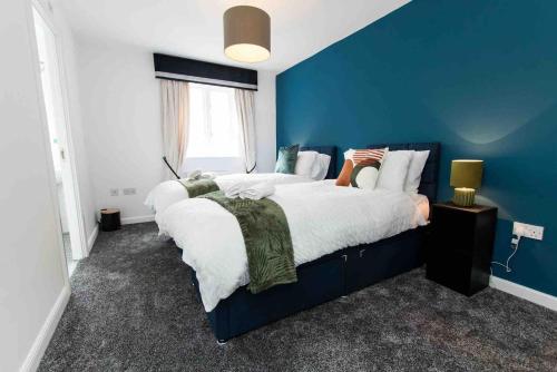 a blue bedroom with a large bed and a blue wall at CLOUDSTAYS - Luxury 3 Bed Townhouse - Sleeps upto 8 Birmingham City and Central - Free Parking & WIFI in Birmingham