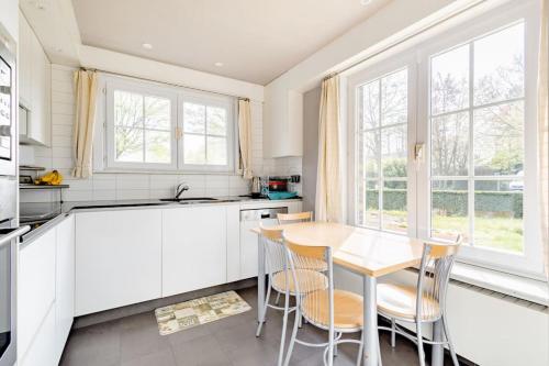 a kitchen with white cabinets and a table and chairs at Private Room in a beautiful Villa in Ghent