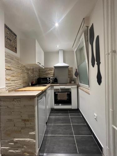 une cuisine avec des armoires blanches et une cuisinière dans l'établissement LE CARRÉ STRASBOURGEOIS - LOGEMENT ENTIER AU CENTRE DU NEUDORF f1, à Strasbourg