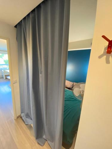 une chambre avec un lit aux murs bleus et un rideau dans l'établissement Nice Stay - Charmant 2p climatisé avec piscine et à 8mn des plages, à Antibes