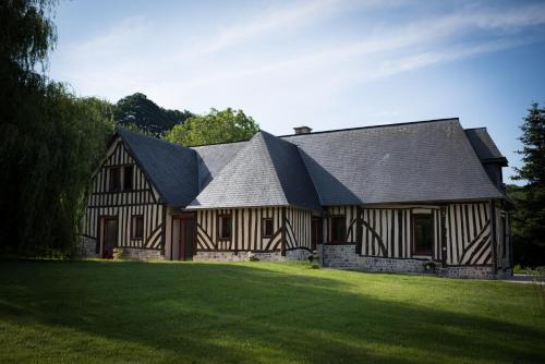 een huis met een zwart dak en een groen gazon bij L'Herbe Haute in Honfleur