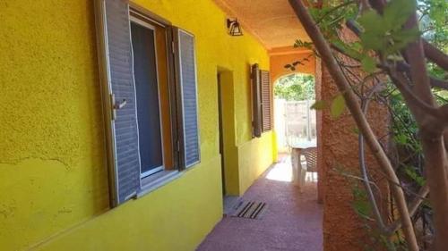 - un bâtiment jaune avec une fenêtre et une terrasse dans l'établissement Vacanze in Sardegna a Posada, à San Giovanni