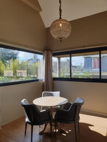une table et des chaises dans une pièce avec des fenêtres dans l'établissement Villa Bayeusaine, maison Bayeux Centre Historique - 3 chambres, à Bayeux