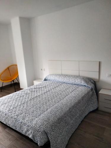 a white bedroom with a bed and a chair at Pedra de Corvos in Fisterra