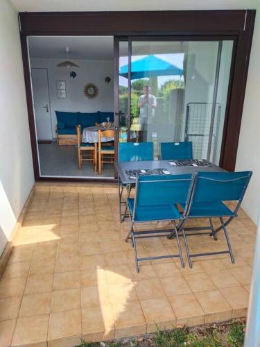 une terrasse avec des chaises bleues et une table avec un parasol dans l'établissement Royan, Vaux sur mer, quartier Pontaillac, 2 pas des plages, à Vaux-sur-Mer