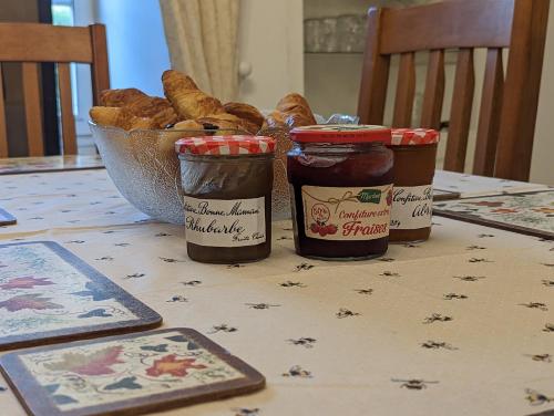 una mesa con tres tarros de mermelada y una cesta de pan en Cottage Tranquillité, en Genouillac