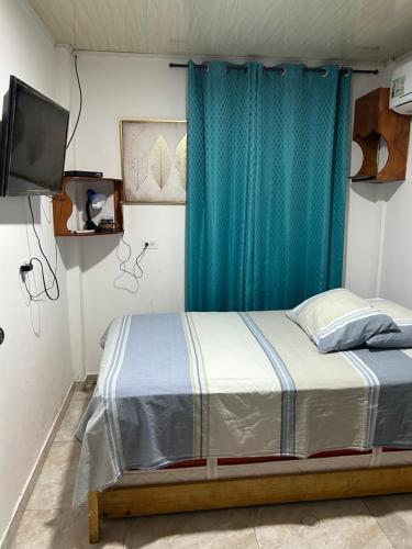 1 dormitorio con 1 cama con cortina azul en Apartamentos Katy, en San Andrés