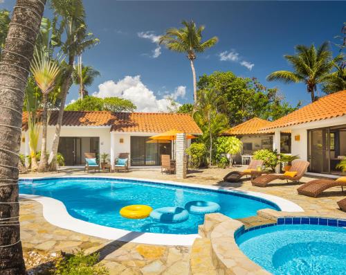 a swimming pool in front of a house with palm trees at Garden By The Sea in Sosúa