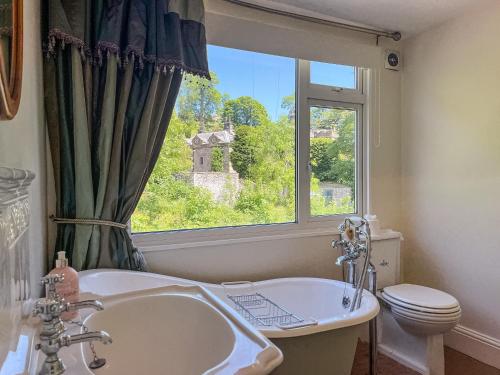 a bathroom with a sink and a toilet and a window at Puddle Duck Cottage in Bakewell