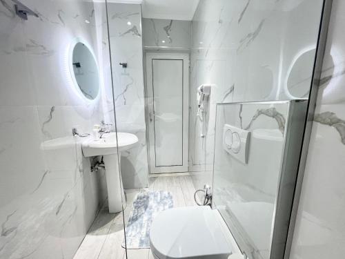 a white bathroom with a toilet and a sink at Dine Apartments in Ksamil