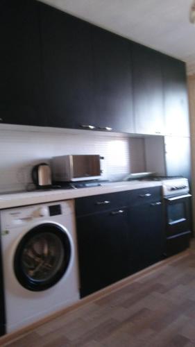 a kitchen with a washing machine and black cabinets at Дубоссары ,ул.Ломоносова 8 А in Corjova