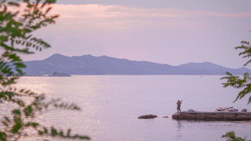 a man standing on a rock in the water fishing at Viva Properties in Ouranoupoli