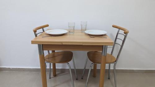 a wooden table with two chairs and two glasses on it at The Brill'S - הברילים in Beʼer Ora