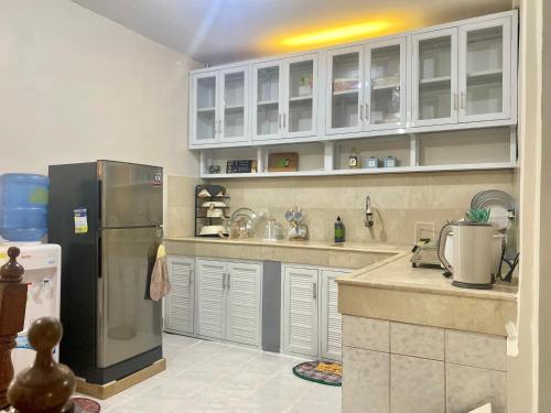 a kitchen with a stainless steel refrigerator and white cabinets at Teo’s Spacious and Affordable Home in Cabanatuan in Cabanatuan