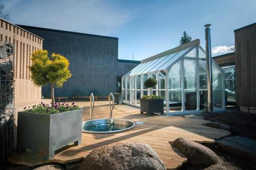 a garden with a glass greenhouse with a tree in it at Three By The Sea apartments at Albatross Home in Ķesterciems