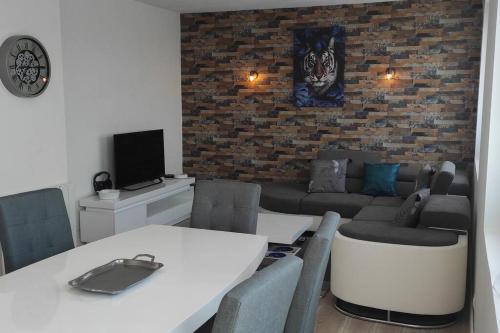 un salon avec un mur de briques, une table et un canapé dans l'établissement Appartement T3 confortable et idéalement situé, à Concarneau